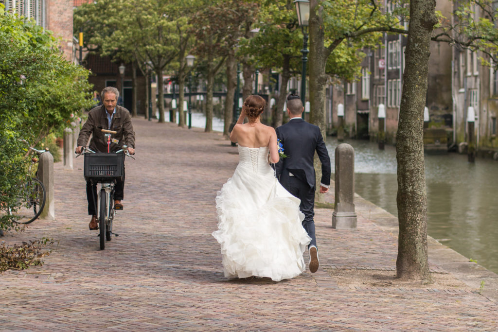 Bruidspaar loopt in Dordrecht en komt man op fiets tegen tijdens fotoshoot, bruidsfotograaf zuid holland