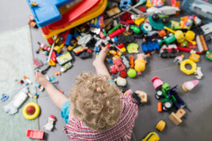 jongetje heeft zijn speelgoedbak omggegooid en zit heerlijk te spelen, documentaire fotografie