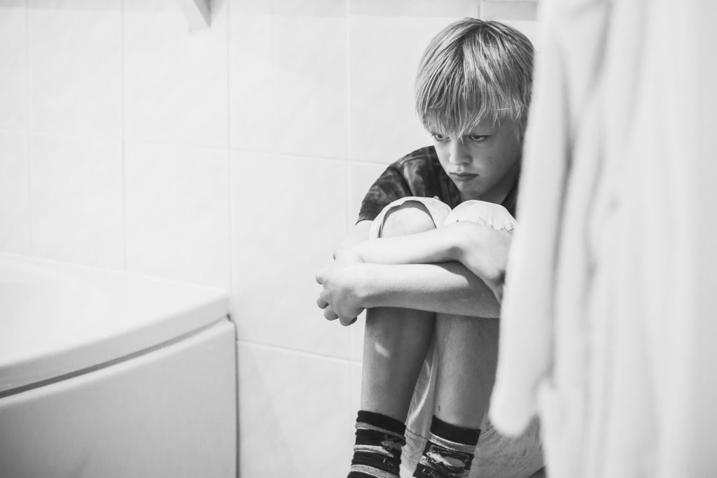 Jongen zit te mokken in de badkamer op de wcpot, day in the life reportage