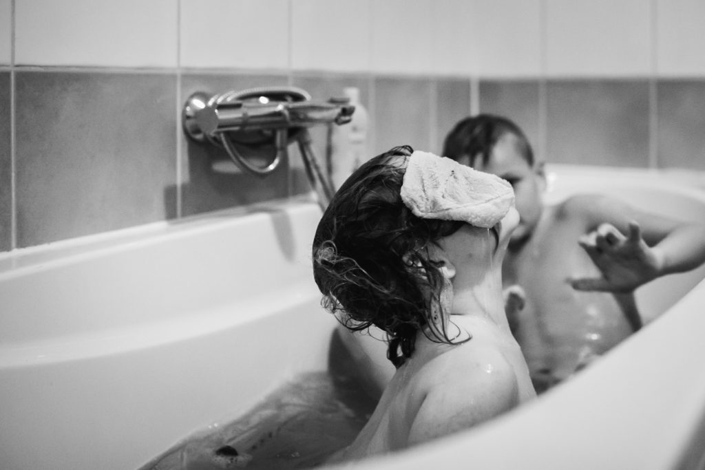 meisje verstopt zich achter een washandje in bad, documentaire fotografie