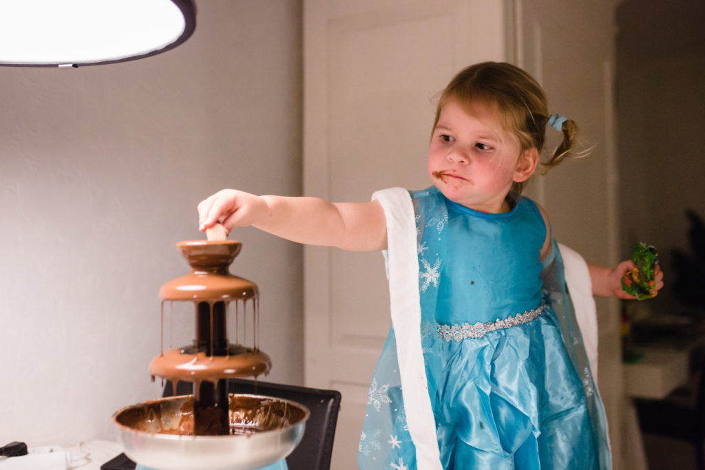 Meisje snoept van chocoladefontein in haar jurk van frozen, documentaire fotografie
