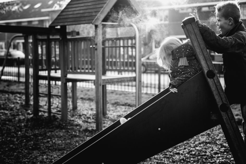 Jongen en meisje spelen in de speeltuin op een koude winterdag, kinderfotografie