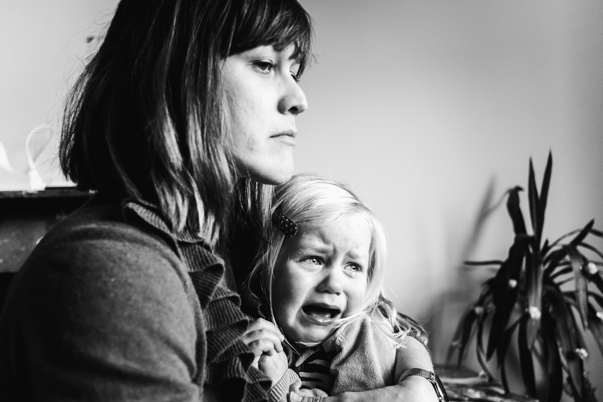 mama kijkt heel boos en streng naar haar zoon terwijl haar dochter huilend op haar schoot zit