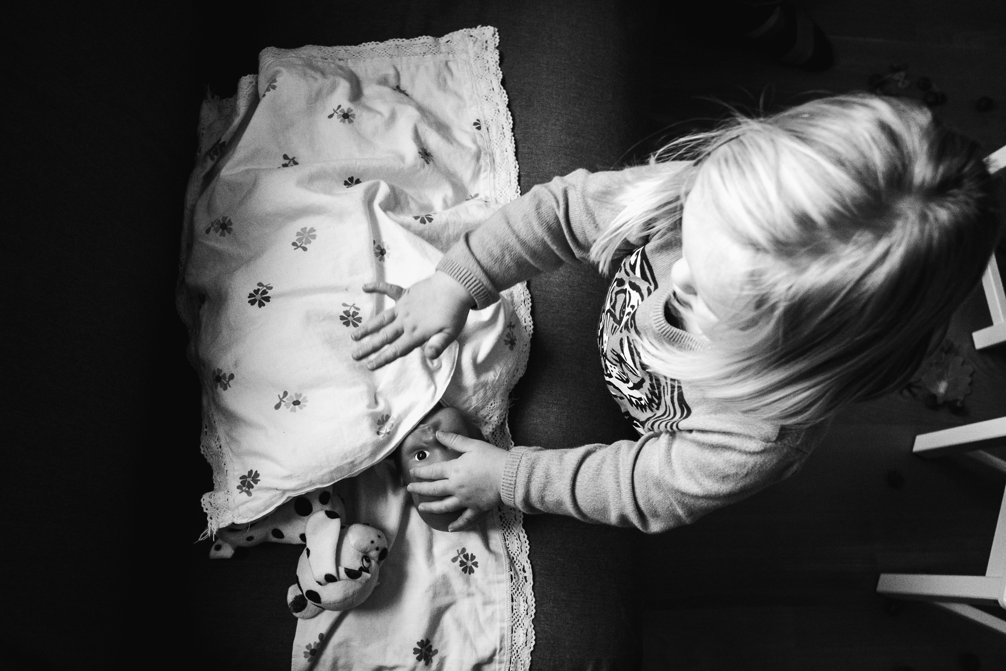 Peuter speelt met haar pop en dekt de pop toe alsof ze in bed ligt