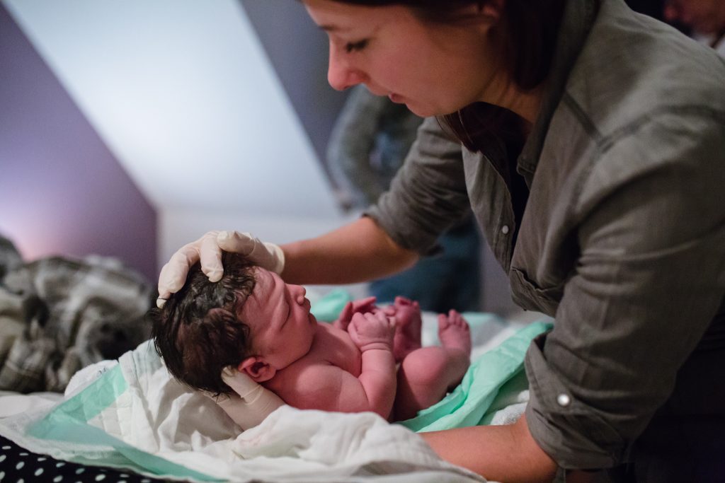 Verloskundige controleert bij net geboren baby of zijn schedel goed is