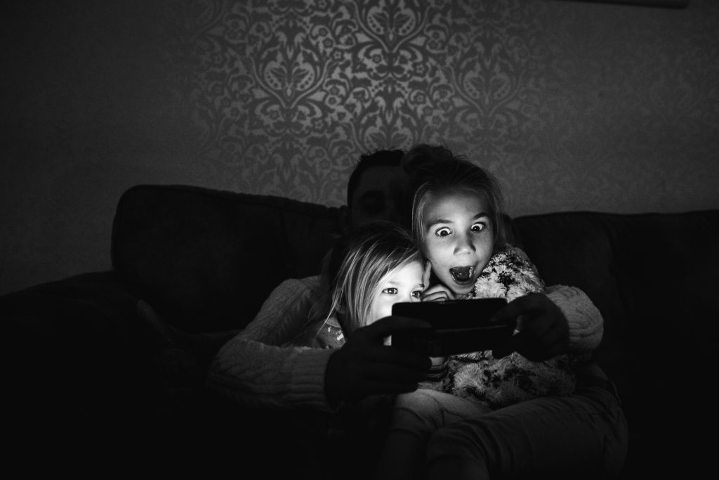 Meisjes kijken in het donker met verschrikte ogen naar Ipad tijdens een day in the life reportage