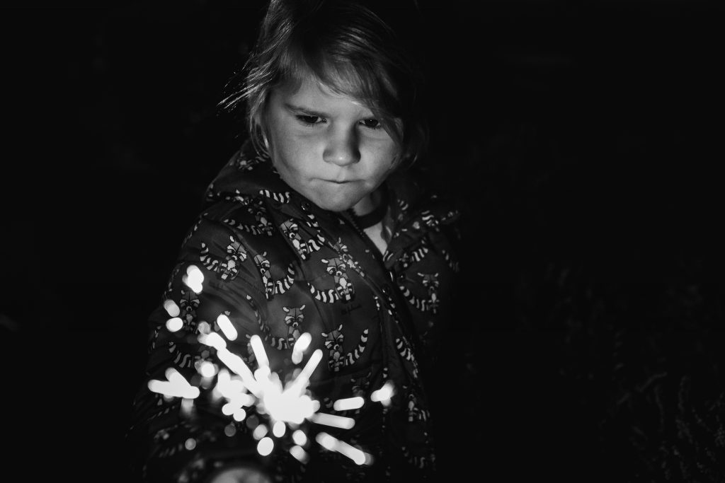Meisje heeft in het donker een sterretje vast om oud en nieuw te vieren, vuurwerk