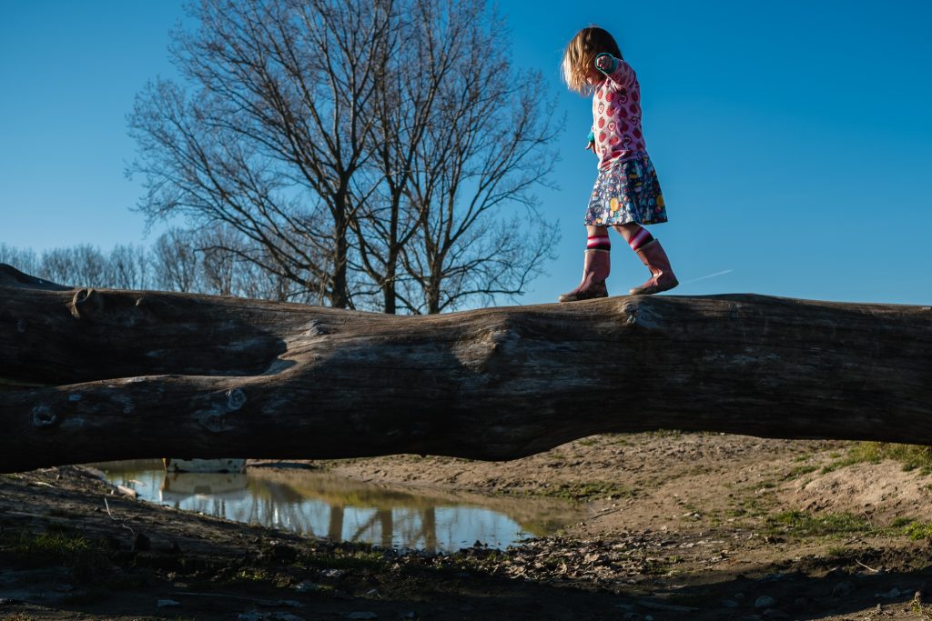 Meisje balanceert over boomstam in natuurspeeltuin Buutenplaets in Ooltgensplaat, Goeree-Overflakkee