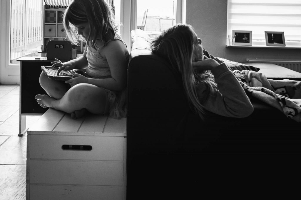 Twee meisjes in een woonkamer, documentaire familiefotografie