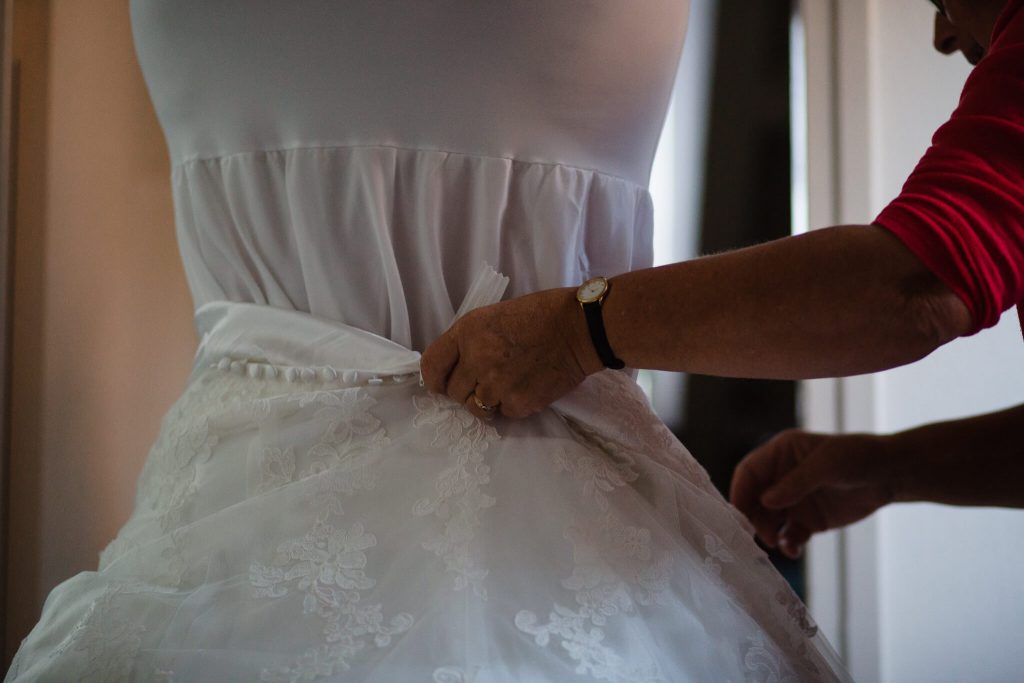 moeder helpt bruid met het aantrekken van de jurk
