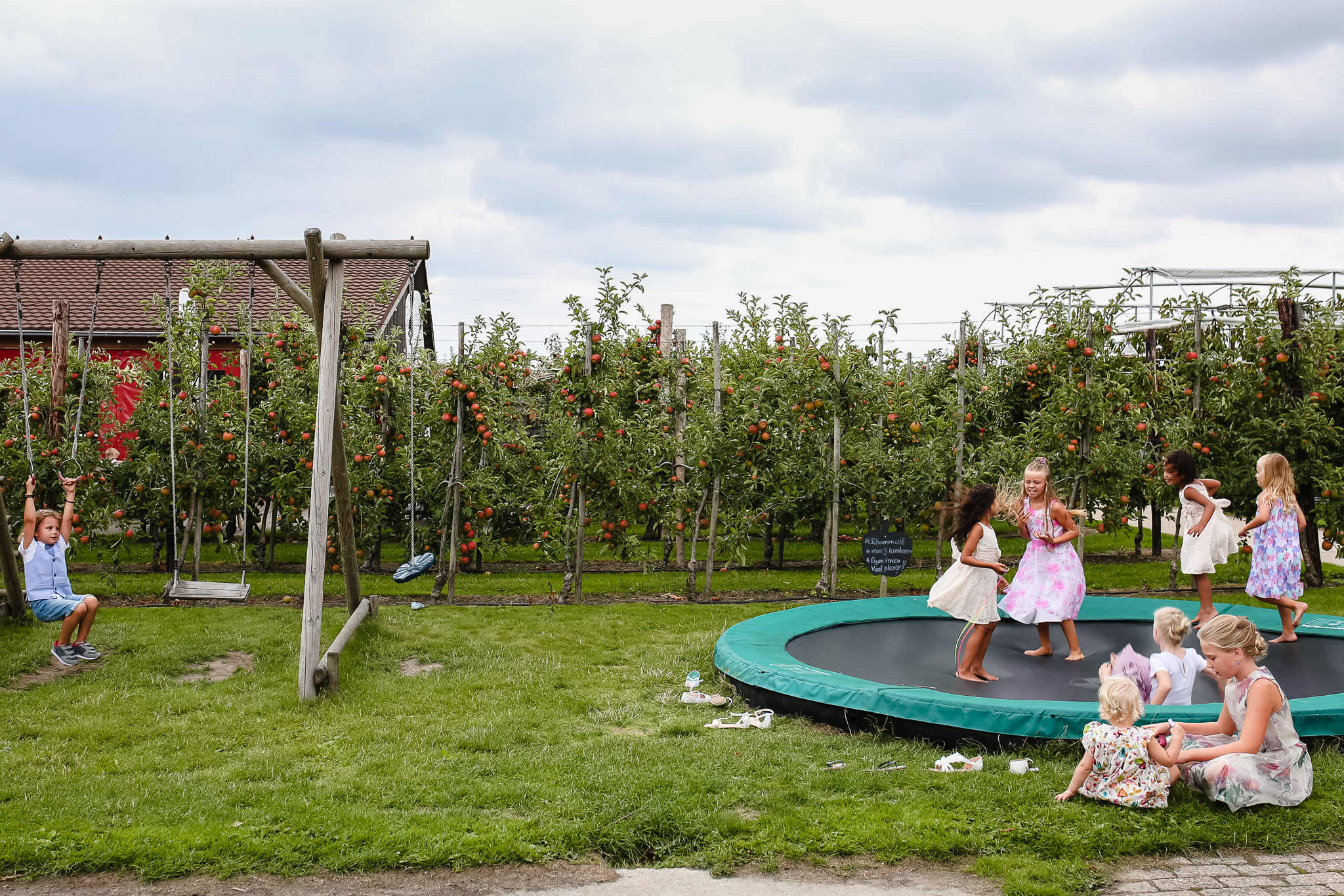 Kinderen op de bruiloft spelen op de trampoline en op het klimtoestel, bruiloften met kinderen, journalistieke bruidsfotografie