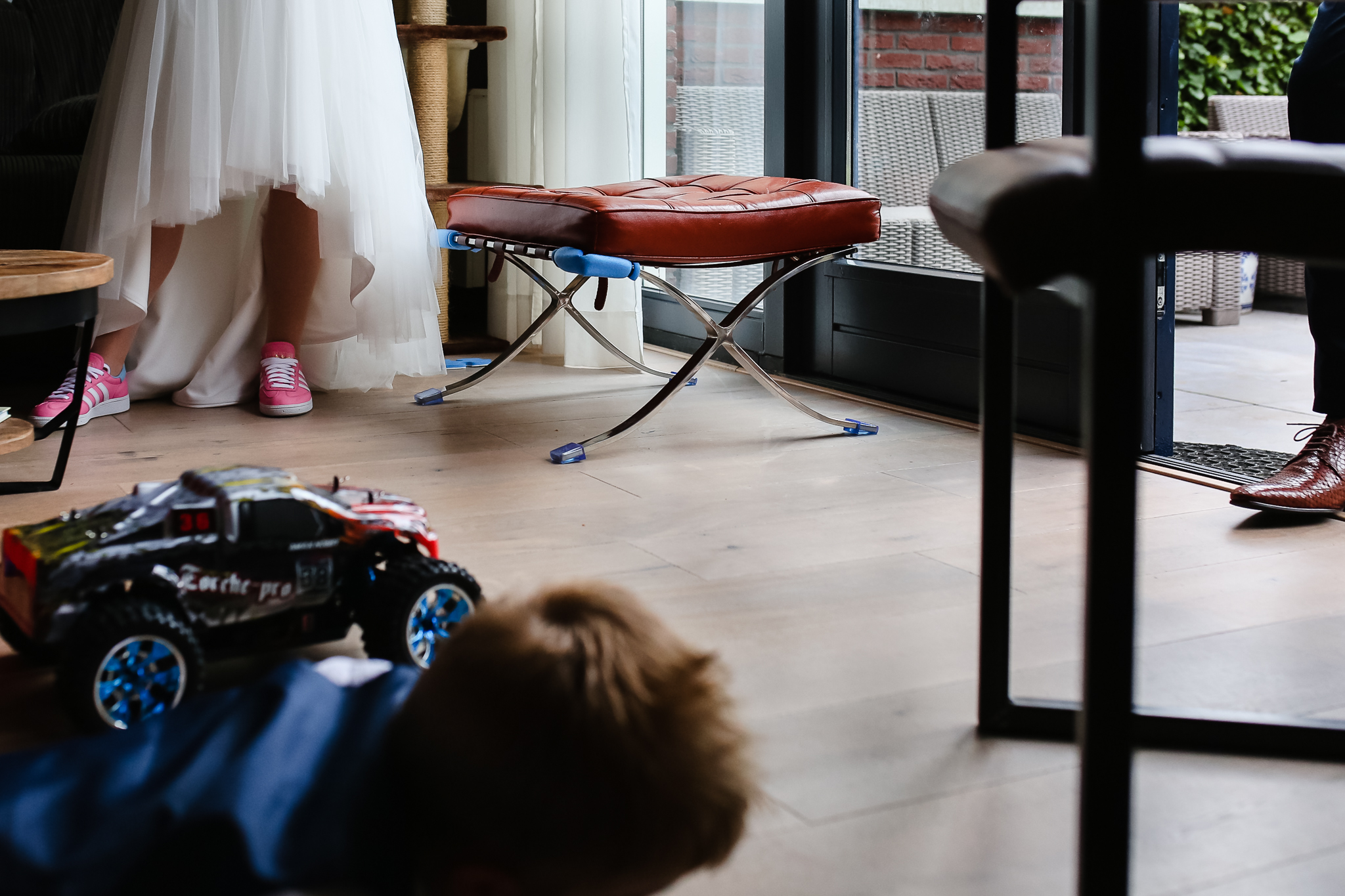 Zoontje speelt op de grond, schoenen van bruid en bruidegom staan er bij, journalistieke bruidsfotografie