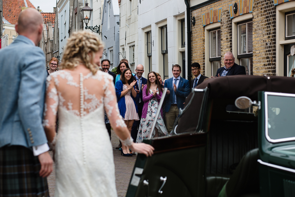 Bruid en bruidegom stappen uit antieke auto in Goedereede op Goeree Overflakkee